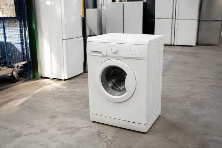 Oude wasmachine op een afgeschermde inzamelplek